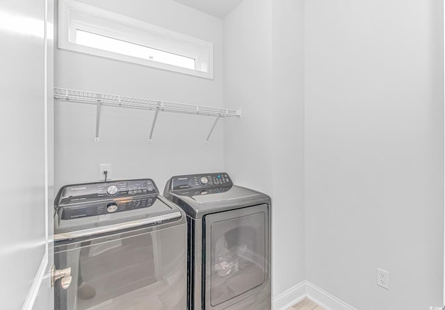 clothes washing area with washing machine and clothes dryer, baseboards, and laundry area