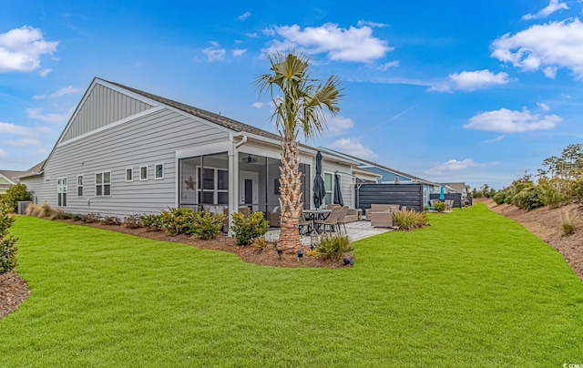 rear view of property featuring a yard, a sunroom, a ceiling fan, and a patio area