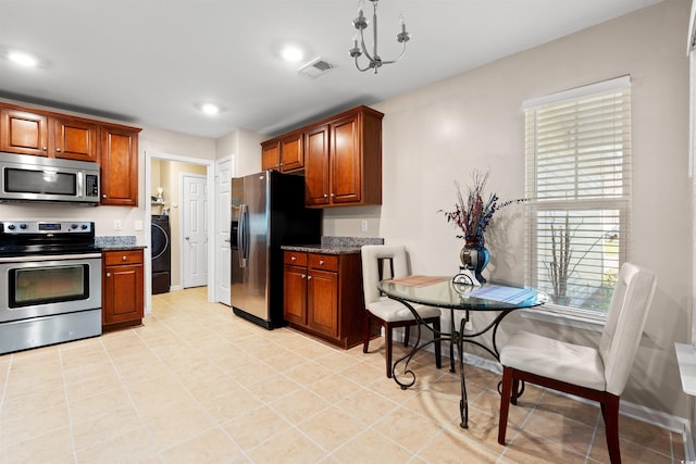 kitchen featuring appliances with stainless steel finishes, washer / dryer, dark stone counters, recessed lighting, and light tile patterned floors