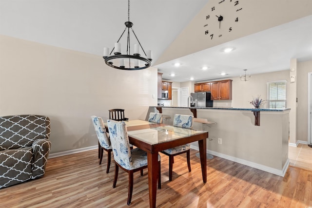 dining space with a chandelier, light wood finished floors, baseboards, high vaulted ceiling, and recessed lighting