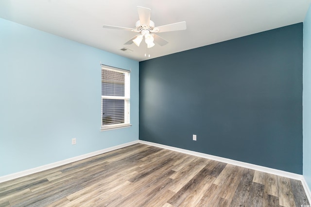 empty room with baseboards, visible vents, a ceiling fan, and wood finished floors