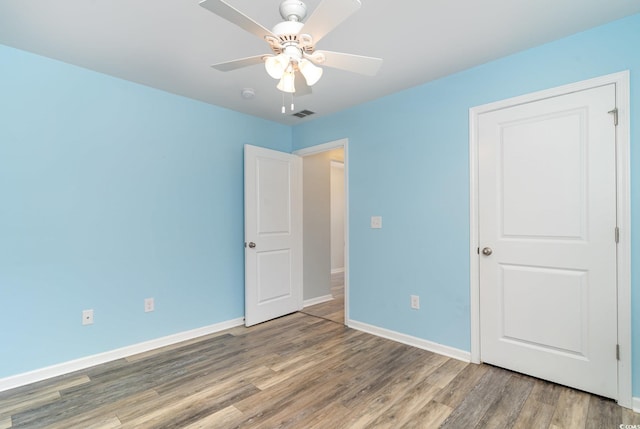 unfurnished bedroom featuring wood finished floors, baseboards, and ceiling fan