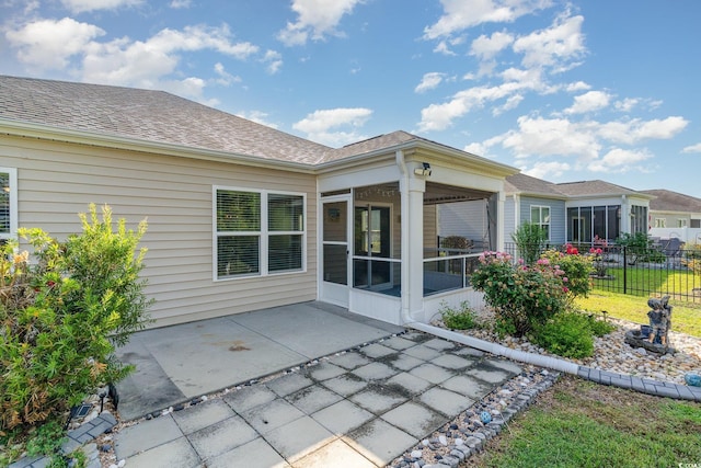 back of house featuring a sunroom, a patio area, roof with shingles, and fence