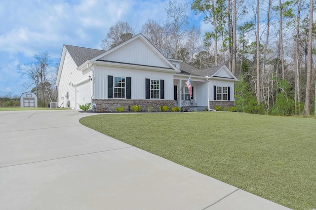 250 Ole Maple St, Loris, SC 29569 - view of front facade with a storage shed, concrete driveway, a front yard, an attached garage, and covered porch