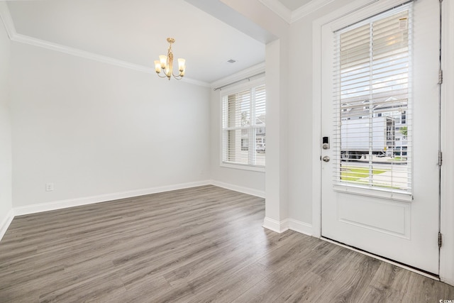 entryway with a chandelier, wood finished floors, ornamental molding, and baseboards