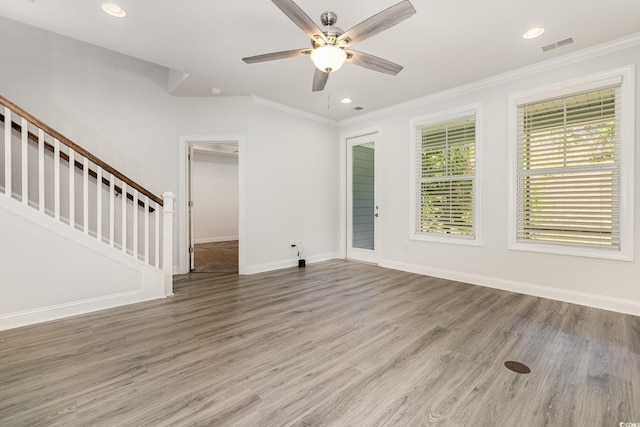 unfurnished living room featuring ornamental molding, ceiling fan, stairs, baseboards, and wood finished floors