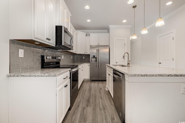kitchen with appliances with stainless steel finishes, a sink, ornamental molding, light wood-type flooring, and white cabinetry