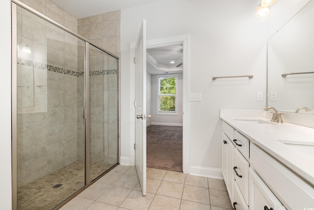 full bathroom featuring a stall shower, baseboards, double vanity, and tile patterned flooring