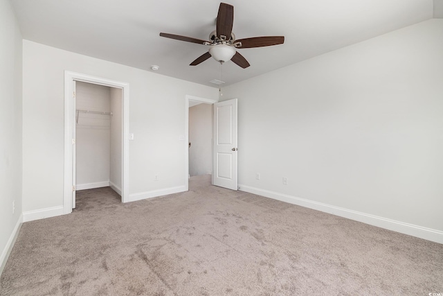 unfurnished bedroom featuring carpet, baseboards, a closet, ceiling fan, and a walk in closet