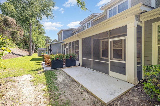 back of property with a sunroom, a patio, and a yard