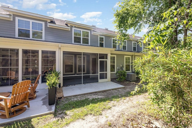 rear view of house featuring a sunroom, a patio area, central AC unit, and roof with shingles