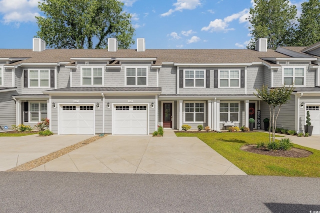 view of front of house with driveway, a chimney, a garage, and a standing seam roof
