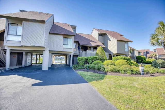 multi unit property featuring roof with shingles, a carport, stairway, driveway, and a residential view