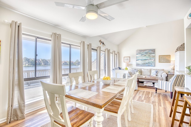 dining area with lofted ceiling, light wood-type flooring, a ceiling fan, and a water view