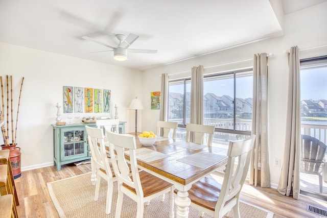 dining area with light wood finished floors, a ceiling fan, and baseboards