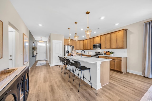 402 Sun Colony Blvd, Longs, SC 29568 - kitchen with appliances with stainless steel finishes, brown cabinets, a kitchen breakfast bar, light wood-type flooring, and a kitchen island with sink