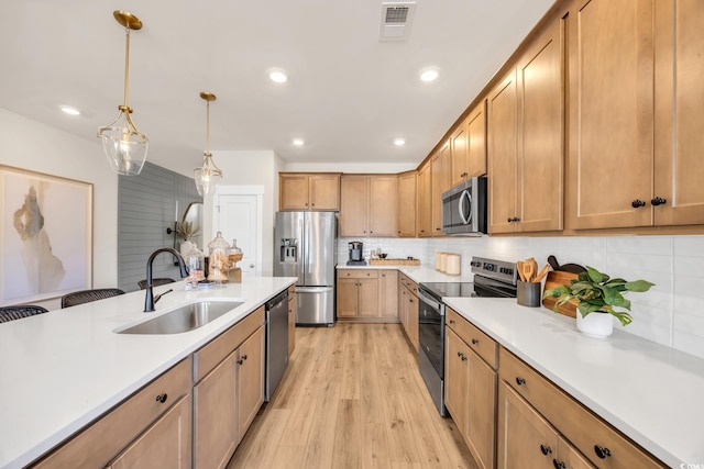kitchen featuring light countertops, stainless steel appliances, light wood-type flooring, and a sink