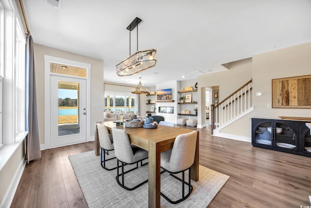 dining area with baseboards, stairs, an inviting chandelier, and light wood-style flooring