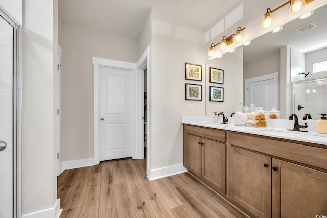 bathroom featuring a stall shower, baseboards, visible vents, a sink, and wood finished floors