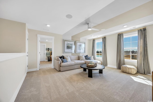 living room with baseboards, ceiling fan, visible vents, and light colored carpet