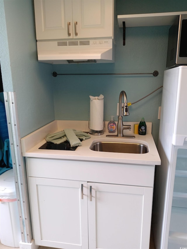 2207 S Ocean Blvd Unit 1407, Myrtle Beach, SC 29577 - kitchen featuring freestanding refrigerator, under cabinet range hood, a sink, light countertops, and white cabinets