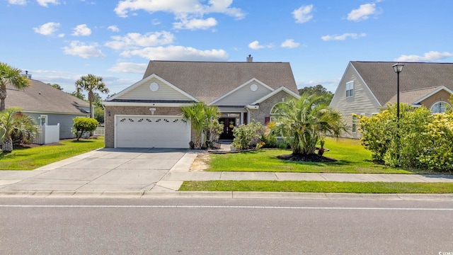 view of front facade featuring a front yard, brick siding, driveway, and a garage