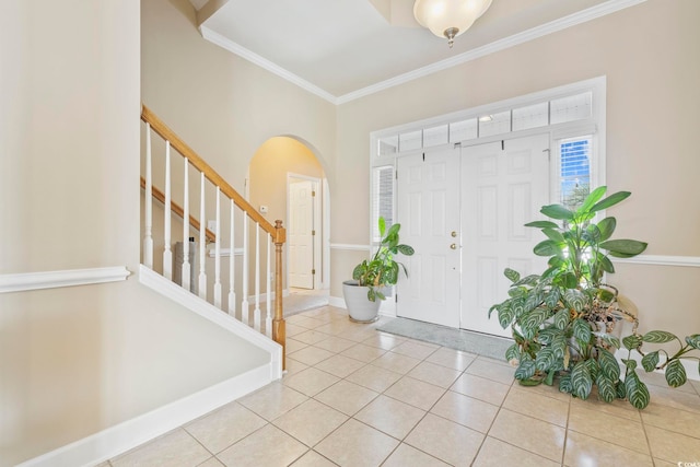 foyer with stairs, ornamental molding, arched walkways, light tile patterned floors, and baseboards