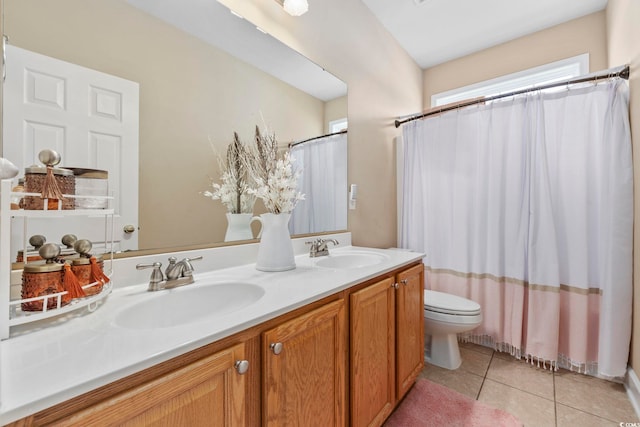 full bathroom featuring toilet, tile patterned flooring, double vanity, and a sink