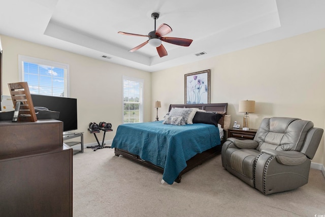 bedroom featuring visible vents, ceiling fan, light carpet, a raised ceiling, and baseboards