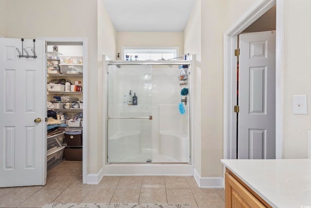 bathroom featuring vanity, baseboards, tile patterned flooring, and a stall shower