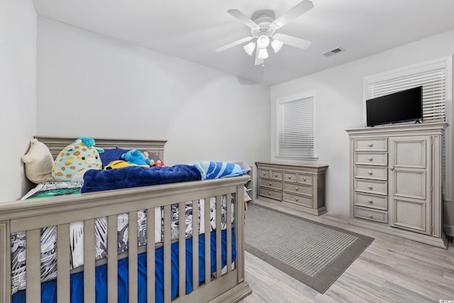 bedroom with ceiling fan, visible vents, and wood finished floors
