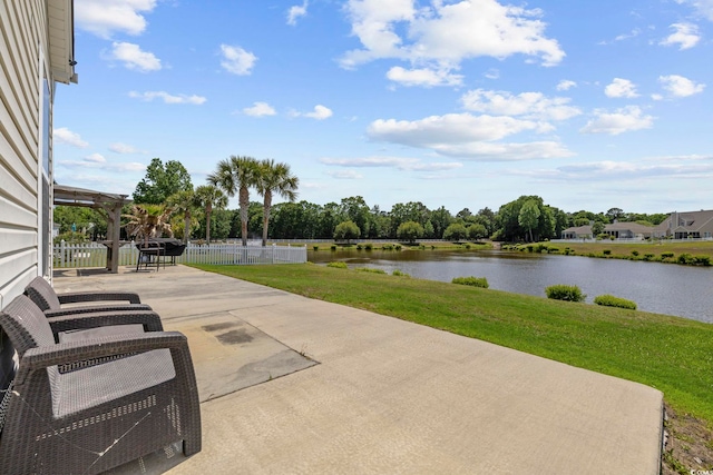 view of patio featuring a water view and fence
