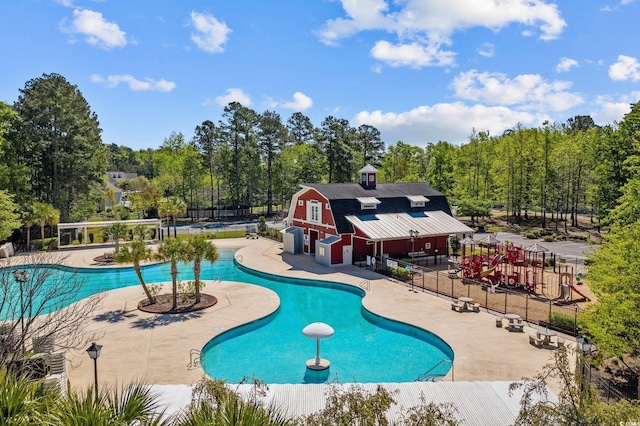 pool with a patio area, fence, and a barn