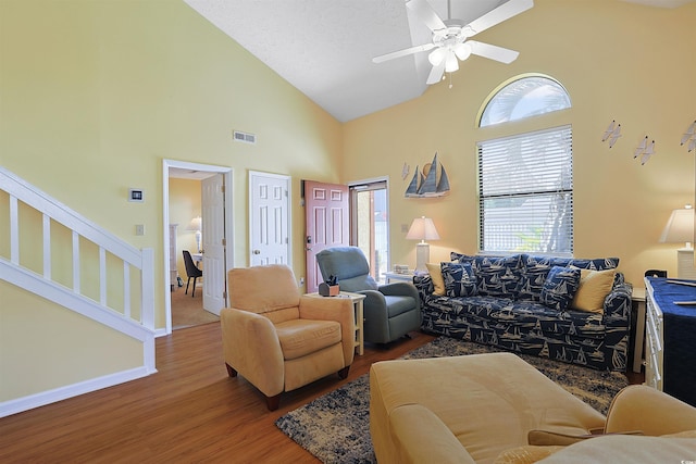 living area with wood finished floors, high vaulted ceiling, ceiling fan, stairs, and baseboards