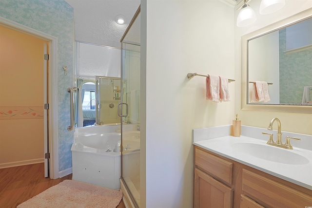 full bath with wood finished floors, a shower stall, wallpapered walls, vanity, and baseboards