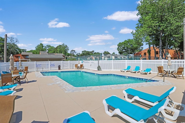 community pool with a patio area and fence
