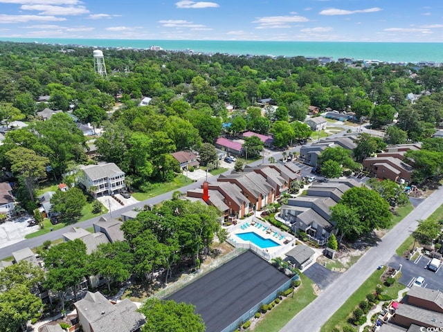 aerial view of residential area featuring a nearby body of water and a pool area