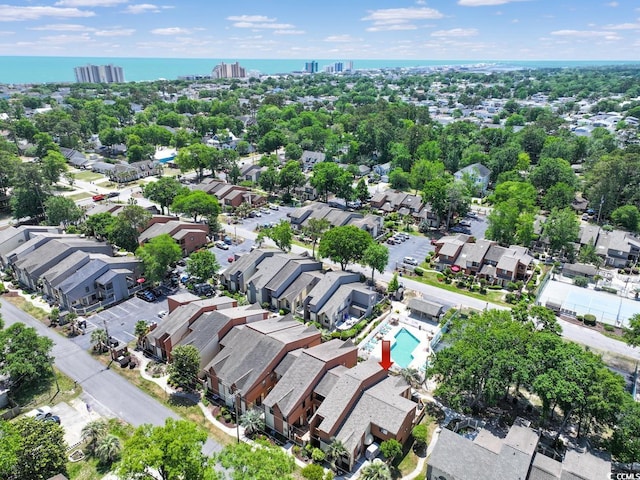 aerial perspective of suburban area featuring a pool area and a large body of water