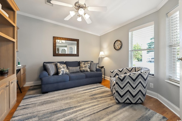 living room with wood finished floors, ornamental molding, baseboards, and ceiling fan