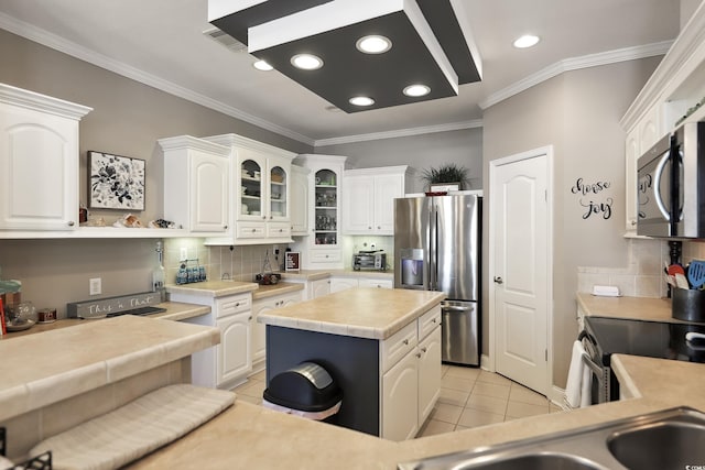 kitchen featuring appliances with stainless steel finishes, white cabinetry, tasteful backsplash, ornamental molding, and recessed lighting