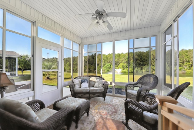 sunroom / solarium with ceiling fan and view of scattered trees