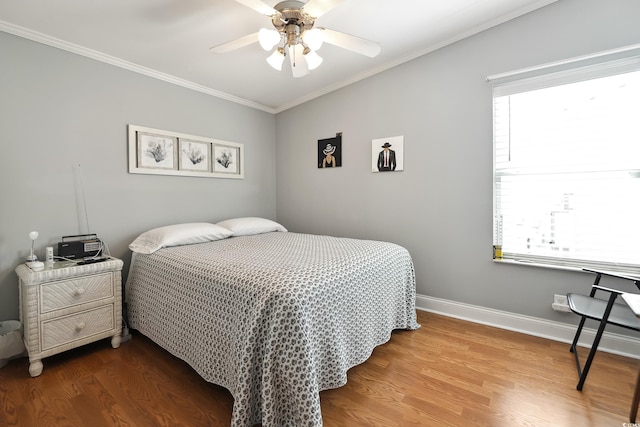 bedroom featuring crown molding, baseboards, wood finished floors, and a ceiling fan
