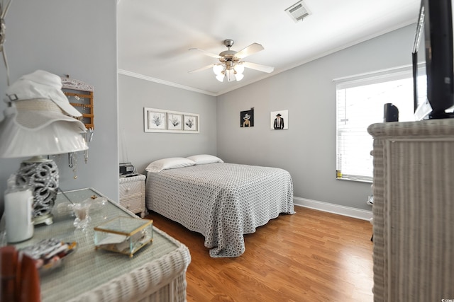bedroom with ornamental molding, wood finished floors, ceiling fan, and baseboards