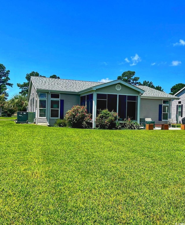 back of house with a sunroom, a yard, and a shingled roof