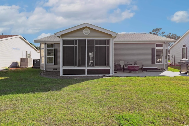 rear view of property featuring a sunroom, a patio area, a lawn, cooling unit, and a shingled roof