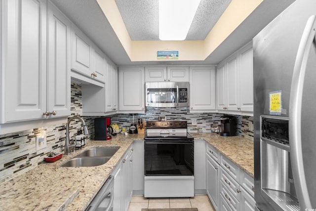 kitchen with stainless steel appliances, a sink, white cabinets, and tasteful backsplash