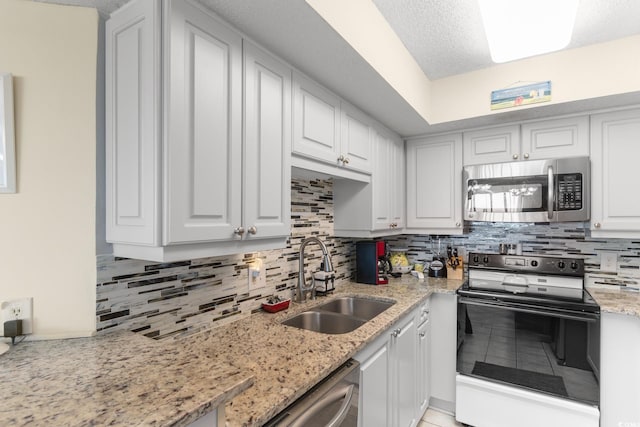 kitchen featuring stainless steel appliances, a sink, tasteful backsplash, and white cabinetry