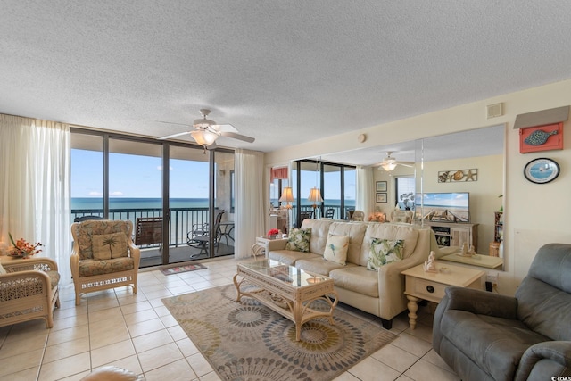 living room featuring a ceiling fan, light tile patterned floors, a textured ceiling, and a water view