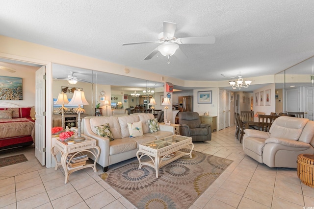 living room with a chandelier, a ceiling fan, light tile patterned floors, and a textured ceiling