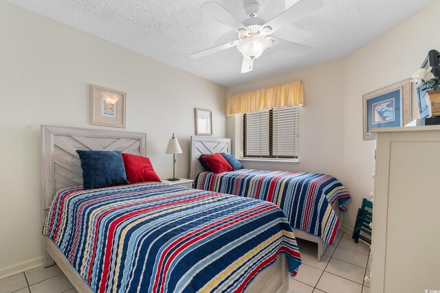 tiled bedroom featuring ceiling fan, a textured ceiling, and baseboards